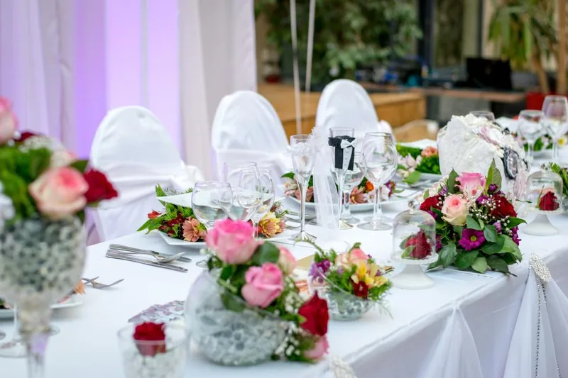 A top table laid with flowers and glassware at a wedding reception